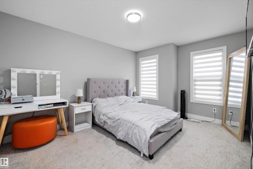 Carpeted bedroom featuring two windows with horizontal blinds, a ceiling-mounted flush light fixture, and light gray painted walls - 714 Ebbers Place, Edmonton, AB - Indoor Photo Showing Bedroom