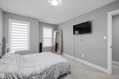 Carpeted bedroom featuring two windows with horizontal blinds, light gray walls, and white trim - 714 Ebbers Place, Edmonton, AB - Indoor Photo Showing Bedroom