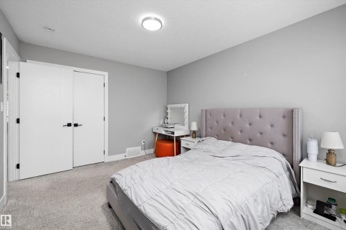 Bedroom featuring a light gray upholstered headboard, wall-to-wall carpeting, and a flush-mount ceiling light - 714 Ebbers Place, Edmonton, AB - Indoor Photo Showing Bedroom