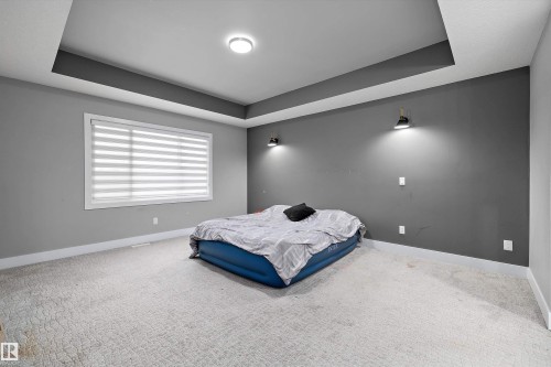 Recessed tray ceiling with integrated lighting, wall-mounted sconces, and a large window with horizontal blinds - 714 Ebbers Place, Edmonton, AB - Indoor Photo Showing Bedroom