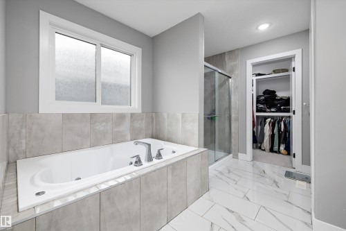 Soaking tub with chrome fixtures, surrounded by large format tile - 714 Ebbers Place, Edmonton, AB - Indoor Photo Showing Bathroom
