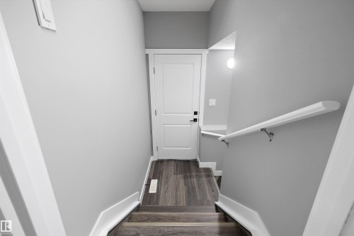 Staircase featuring wood-finish treads and risers, white baseboards, and a white handrail - 714 Ebbers Place, Edmonton, AB - Indoor Photo Showing Other Room