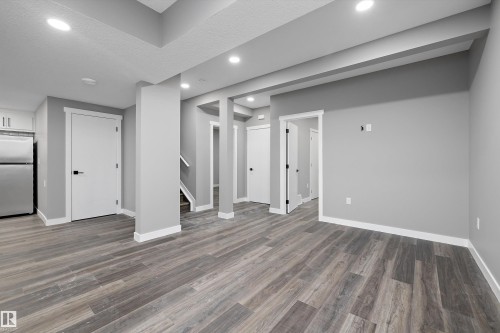Open-concept living area featuring wood-finish flooring, recessed lighting, neutral gray wall tones, and white trim - 714 Ebbers Place, Edmonton, AB - Indoor Photo Showing Other Room