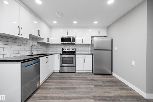 Modern kitchen featuring white cabinetry, dark countertops, and a subway tile backsplash - 714 Ebbers Place, Edmonton, AB - Indoor Photo Showing Kitchen With Stainless Steel Kitchen With Upgraded Kitchen