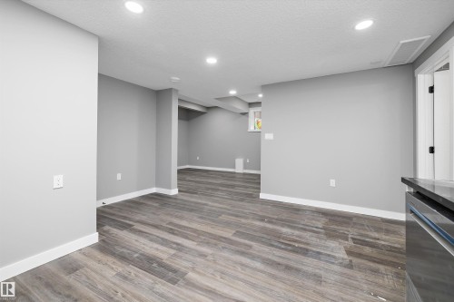 Spacious finished basement featuring wood-finish flooring, recessed lighting, and light gray walls with white trim - 714 Ebbers Place, Edmonton, AB - Indoor