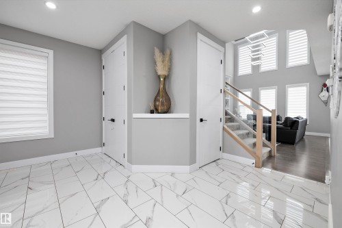 Foyer showcasing large format tile flooring, a contemporary staircase with clear panel railing, and recessed lighting - 714 Ebbers Place, Edmonton, AB - Indoor Photo Showing Other Room