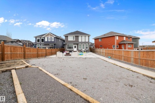 Expansive gravel yard featuring a wood privacy fence, concrete patio, and a built-in fire pit - 714 Ebbers Place, Edmonton, AB - Outdoor