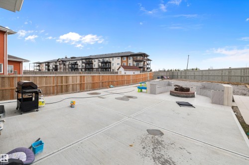 Expansive concrete patio featuring a built-in fire pit with brick surround, integrated stone-finish seating, and wood privacy fencing - 714 Ebbers Place, Edmonton, AB - Outdoor