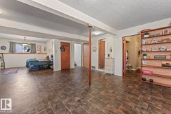 Spacious room featuring wood-finish flooring, exposed ceiling beams, and a window with natural light - 