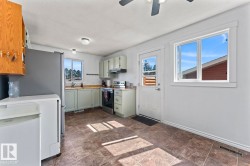 Kitchen featuring tile flooring, light-colored cabinetry, a stainless steel range, and multiple windows - 