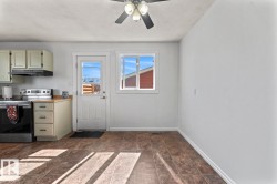 Kitchen area with a ceiling fan, light-toned cabinetry, stainless steel range, and a door with a window - 