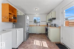 Kitchen featuring light-toned cabinetry, wood-finish countertops, stainless steel appliances, and a tiled floor - 