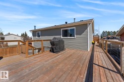 Spacious wood deck with natural wood railing, featuring a ramp entrance and steps to lower level - 