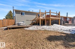 Backyard featuring a multi-level wood deck, wood privacy fence, and a neutral-toned exterior siding - 