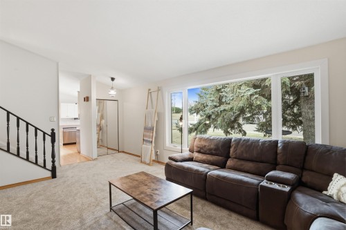 Spacious living area featuring expansive windows, neutral wall tones, and plush carpet flooring - 23 Clearwater, Devon, AB - Indoor Photo Showing Living Room