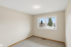 Neutral-toned room featuring a white-framed window, textured ceiling, and light gray carpeting - 