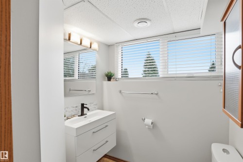Bathroom featuring a floating vanity with integrated sink, black wall-mounted faucet, and a horizontally mounted mirror - 23 Clearwater, Devon, AB - Indoor Photo Showing Bathroom
