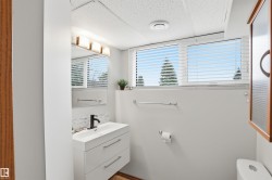 Bathroom featuring a floating vanity with integrated sink, black wall-mounted faucet, and a horizontally mounted mirror - 