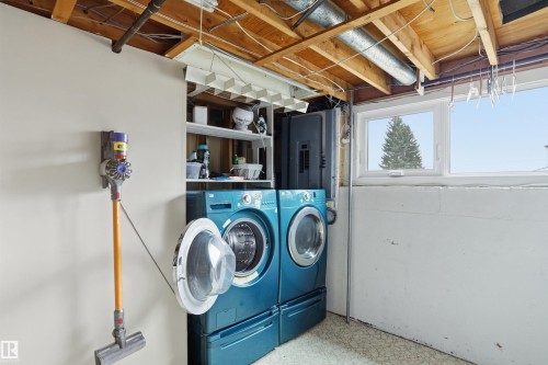 Dedicated laundry area featuring a front-loading washer and dryer set, an exposed beam ceiling, a window, and durable vinyl flooring - 23 Clearwater, Devon, AB - Indoor Photo Showing Laundry Room