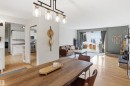 Open-concept living and dining areas featuring wood-finish flooring, a contemporary linear chandelier, and sliding glass doors to the exterior - 23 Clearwater, Devon, AB  - Indoor 
