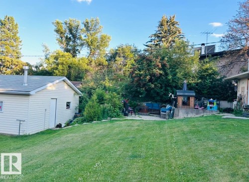 Expansive lawn area with a detached outbuilding featuring vinyl siding and a shingled roof - 23 Clearwater, Devon, AB - Outdoor
