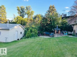 Expansive lawn area with a detached outbuilding featuring vinyl siding and a shingled roof - 