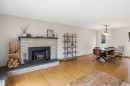 Brick-front fireplace with a dark wood mantel and hearth - 23 Clearwater, Devon, AB  - Indoor Photo Showing Living Room With Fireplace 