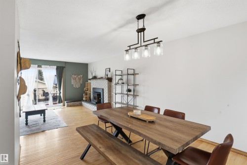 Light wood-finish flooring extends through this open living space - 23 Clearwater, Devon, AB - Indoor With Fireplace