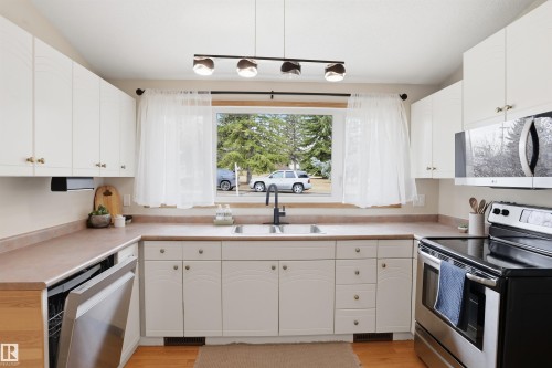 Kitchen featuring white cabinetry, light wood-finish flooring, and a stainless steel dishwasher - 23 Clearwater, Devon, AB - Indoor Photo Showing Kitchen With Double Sink