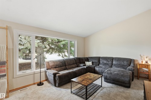 Living area featuring a spacious window, neutral wall tones, and light-colored carpeting - 23 Clearwater, Devon, AB - Indoor Photo Showing Living Room