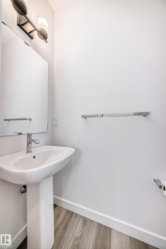 Pedestal sink with chrome faucet, large rectangular wall mirror, and modern vanity light fixture - 38 1910 Collip View, Edmonton, AB - Indoor Photo Showing Bathroom
