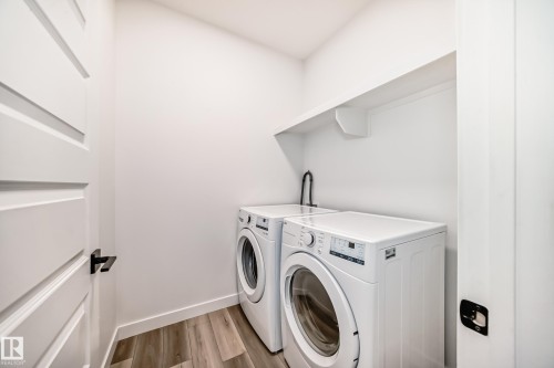 Dedicated laundry area featuring wood-finish flooring, a wall-mounted shelf, and a utility faucet - 38 1910 Collip View, Edmonton, AB - Indoor Photo Showing Laundry Room
