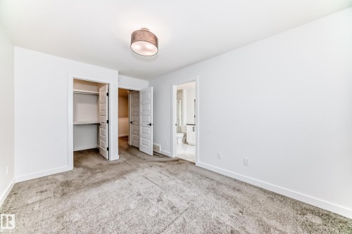 Carpeted room featuring white walls, a flush-mount ceiling light fixture, a closet with bifold doors, and an entry to a bathroom with a vanity and toilet - 38 1910 Collip View, Edmonton, AB - Indoor Photo Showing Other Room