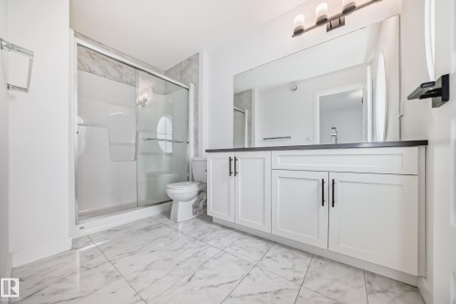 Bathroom featuring a spacious shower with sliding glass doors and marble-look wall tile - 38 1910 Collip View, Edmonton, AB - Indoor Photo Showing Bathroom