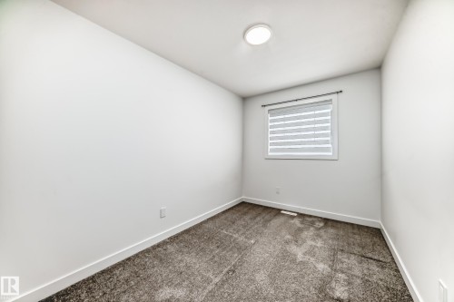 Neutral white wall paint, grey carpet, and a single window with blinds - 38 1910 Collip View, Edmonton, AB - Indoor Photo Showing Other Room