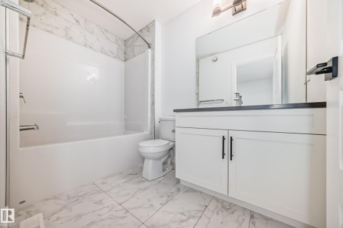 Bathroom featuring a white vanity with flat-panel doors and black hardware, a dark countertop, and a large wall-mounted mirror - 38 1910 Collip View, Edmonton, AB - Indoor Photo Showing Bathroom