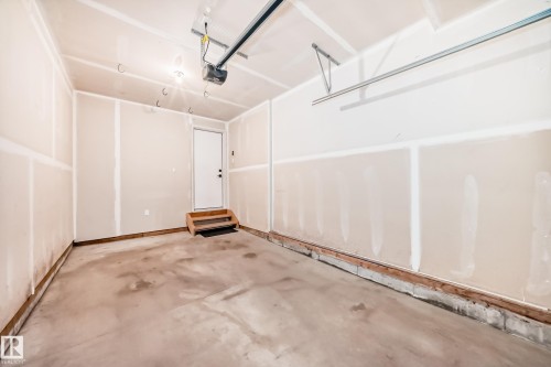 Attached garage featuring a concrete floor, unfinished drywall, and an overhead door opener mechanism - 38 1910 Collip View, Edmonton, AB - Indoor Photo Showing Garage