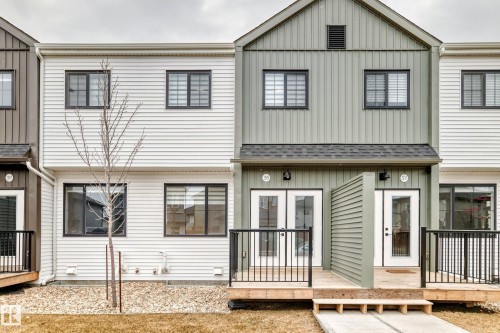 Townhome exterior featuring a combination of horizontal siding and vertical paneling, black-framed windows, and private elevated decks with black metal railings - 38 1910 Collip View, Edmonton, AB - Outdoor