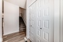 Entryway featuring paneled bifold doors, wood-finish flooring, white baseboards, and a carpeted staircase with a light wood handrail - 38 1910 Collip View, Edmonton, AB  - Indoor Photo Showing Other Room 