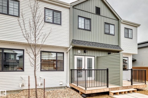 Rear exterior featuring a wooden deck with black metal railings, white French doors, and two-tone siding - 38 1910 Collip View, Edmonton, AB - Outdoor