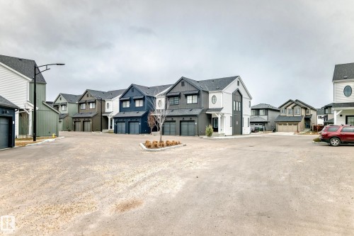 Modern townhome community featuring varied exterior color palettes, dark-framed windows, attached garages, and pitched roofs - 38 1910 Collip View, Edmonton, AB - Outdoor With Facade