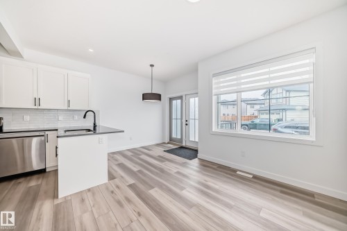 Modern kitchen featuring white cabinetry, stainless steel appliances, and a dark countertop island with a built-in sink - 38 1910 Collip View, Edmonton, AB - Indoor Photo Showing Kitchen
