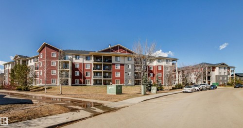 Multi-story residential buildings featuring red and beige siding with stone accents - 208 18122 77 Street, Edmonton, AB - Outdoor With Facade