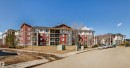 Multi-story residential buildings featuring red and beige siding with stone accents - 208 18122 77 Street, Edmonton, AB  - Outdoor With Facade 