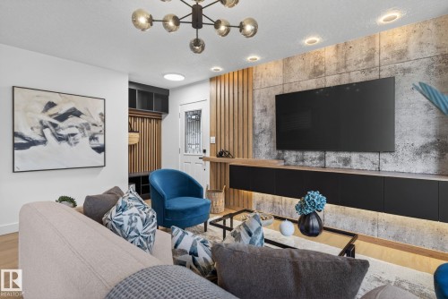Living area featuring wood-finish flooring, a contemporary chandelier, recessed ceiling lighting, and a feature wall with a large built-in media console - 13332 106 Street, Edmonton, AB - Indoor