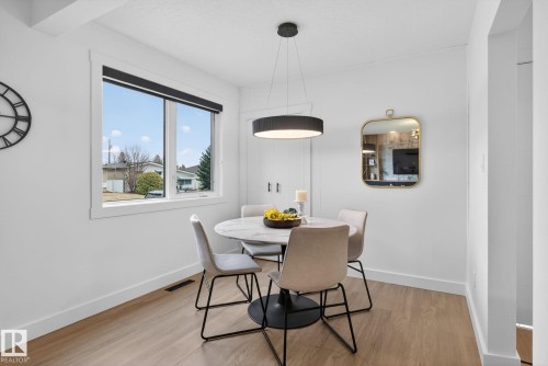 Dining area featuring a modern pendant light fixture, wood-finish flooring, and a large window with black roller blinds - 13332 106 Street, Edmonton, AB - Indoor Photo Showing Dining Room