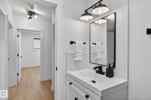 Bathroom vanity featuring a rectangular sink, matte black hardware, and vertical tile backsplash - 13332 106 Street, Edmonton, AB - Indoor Photo Showing Bathroom