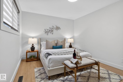 Bright interior space featuring light-toned walls, wood-finish flooring, and a large window with horizontal blinds - 13332 106 Street, Edmonton, AB - Indoor Photo Showing Bedroom