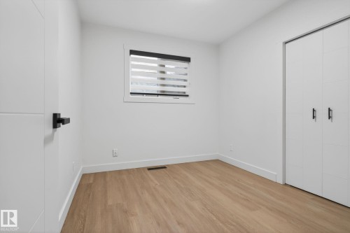 Bright room featuring wood-finish flooring, white walls, and a window with horizontal blinds - 13332 106 Street, Edmonton, AB - Indoor Photo Showing Other Room