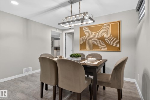 Dining area featuring light grey walls, wood-finish flooring, recessed ceiling lighting, and a contemporary linear chandelier - 13332 106 Street, Edmonton, AB - Indoor Photo Showing Dining Room